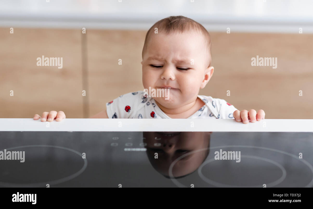 Baby boy reaching to hot electric stove Stock Photo