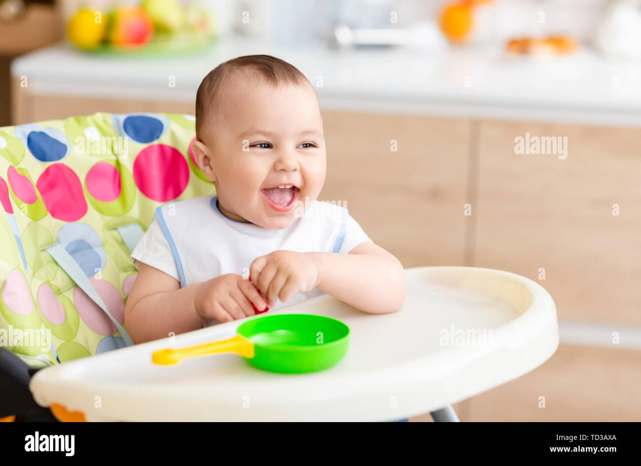 Happy baby sitting in high chair in kitchen Stock Photo