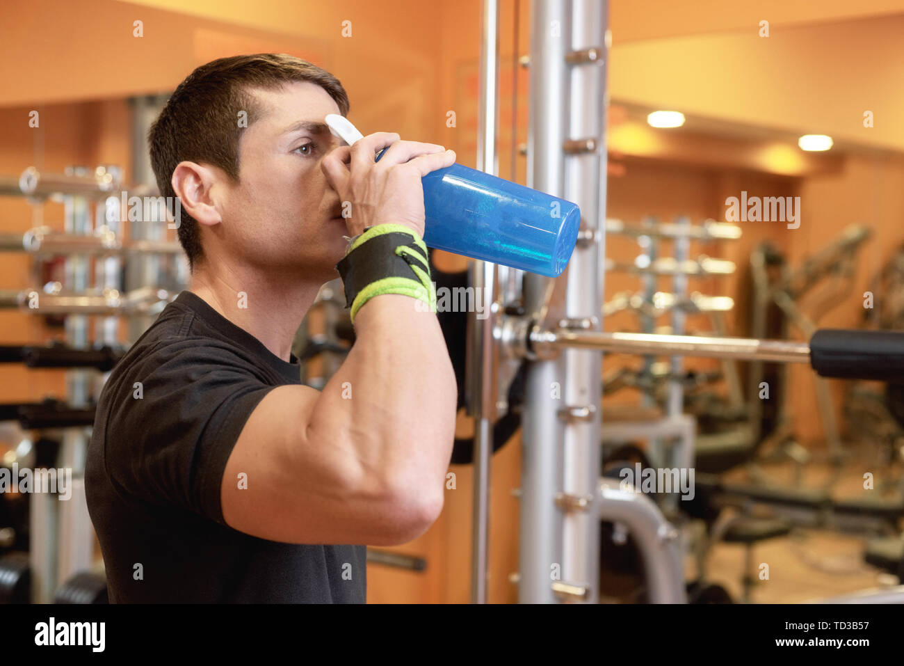 Muscular man drink water from blue bottle in the gym Stock Photo - Alamy