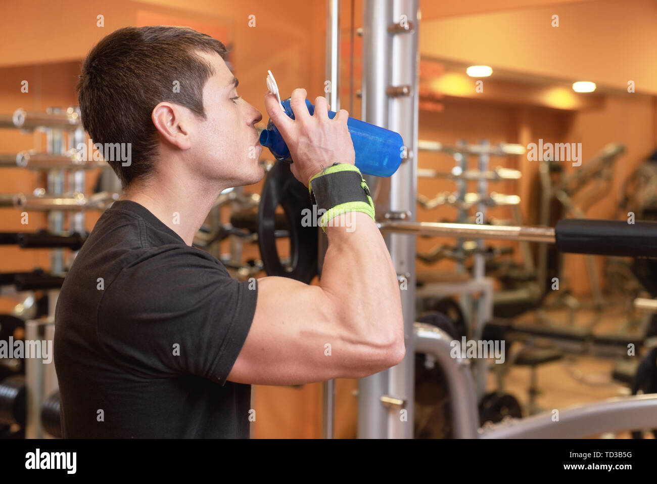 Muscular man drink water from blue bottle in the gym Stock Photo - Alamy