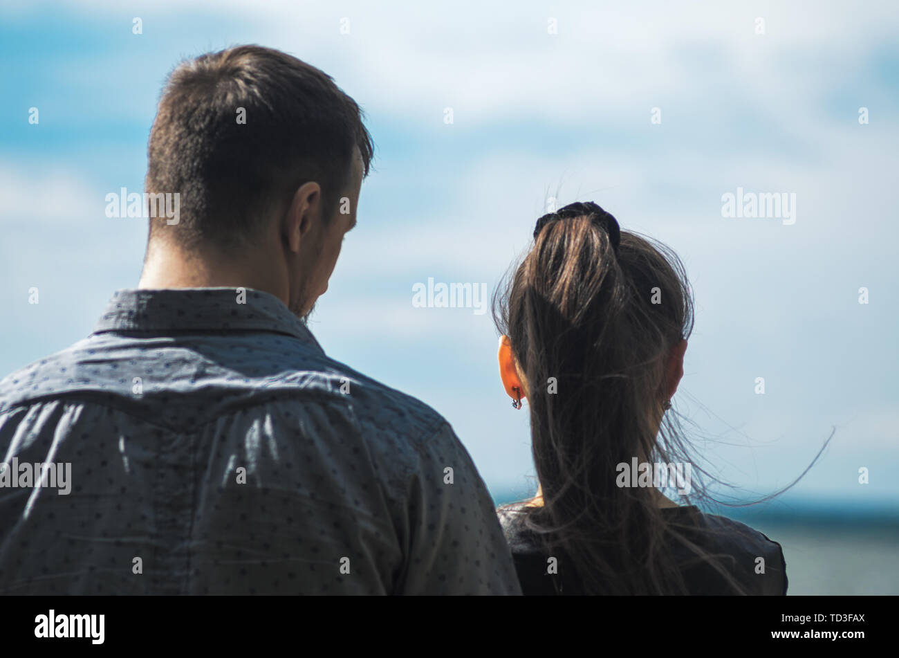 Couple stands on the shore of the lake. Backs of man and woman Stock Photo