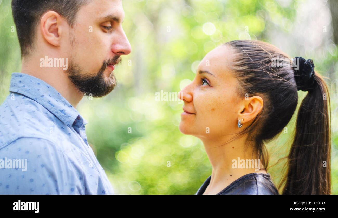 Outdoor portrait of a couple in love. Man and young woman with long ponytail hair look at each other Stock Photo