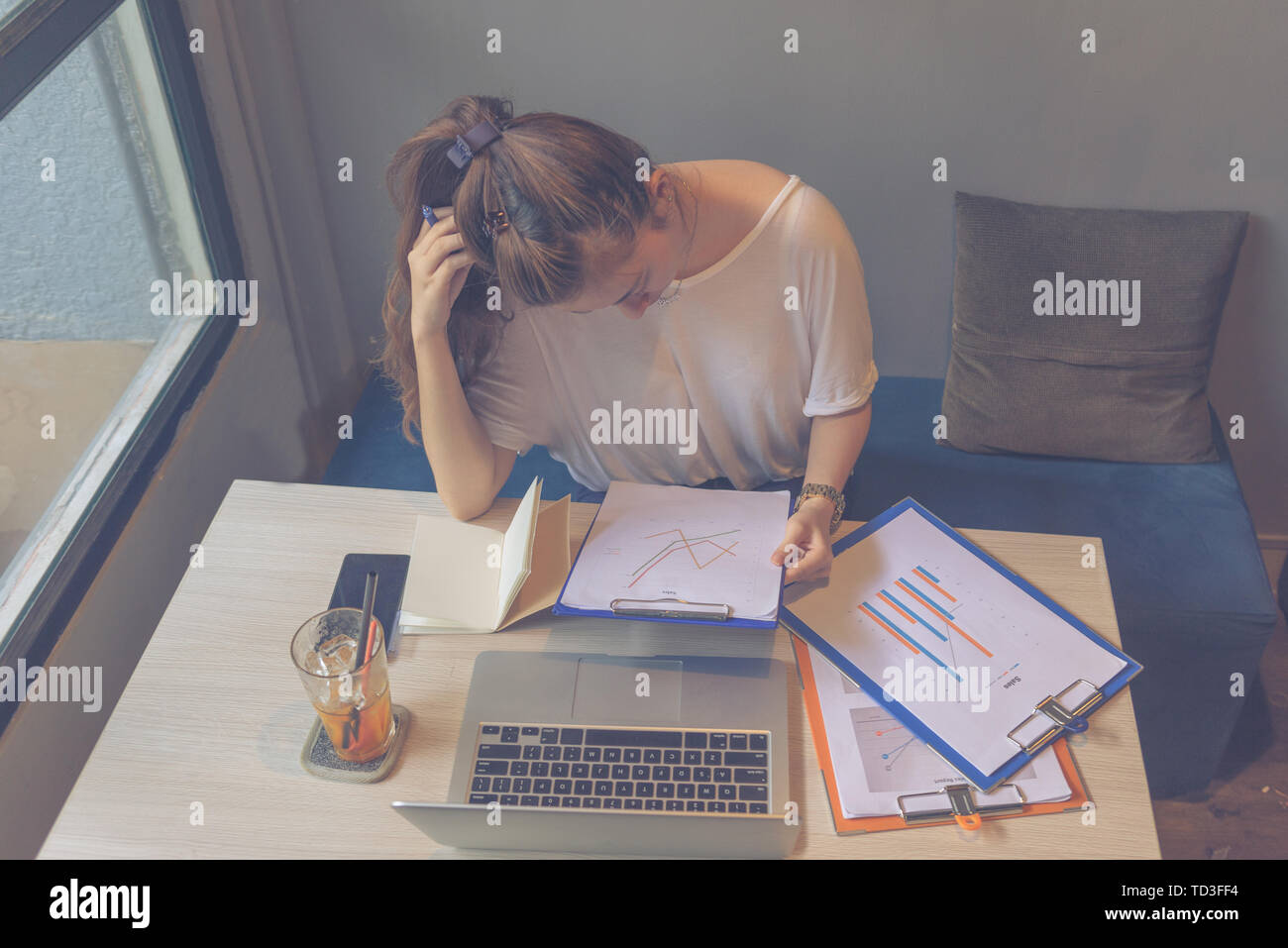 Young lady focusing on analyzing sales chart document with laptop Stock Photo