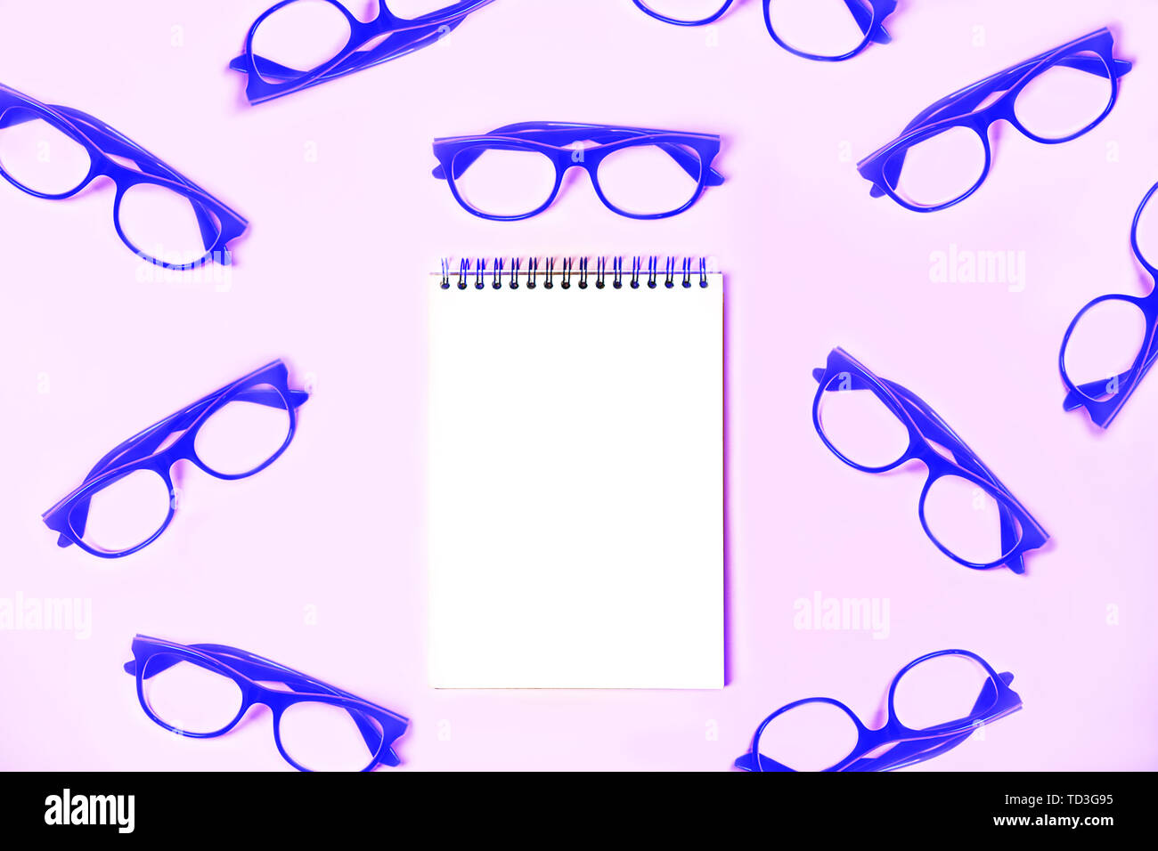 Notepad with trendy glasses on pastel pink violet background Stock