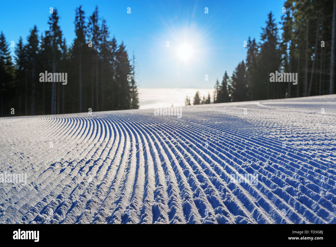 Fresh groomed ski slope close-up against rising sun in the mountains Stock Photo