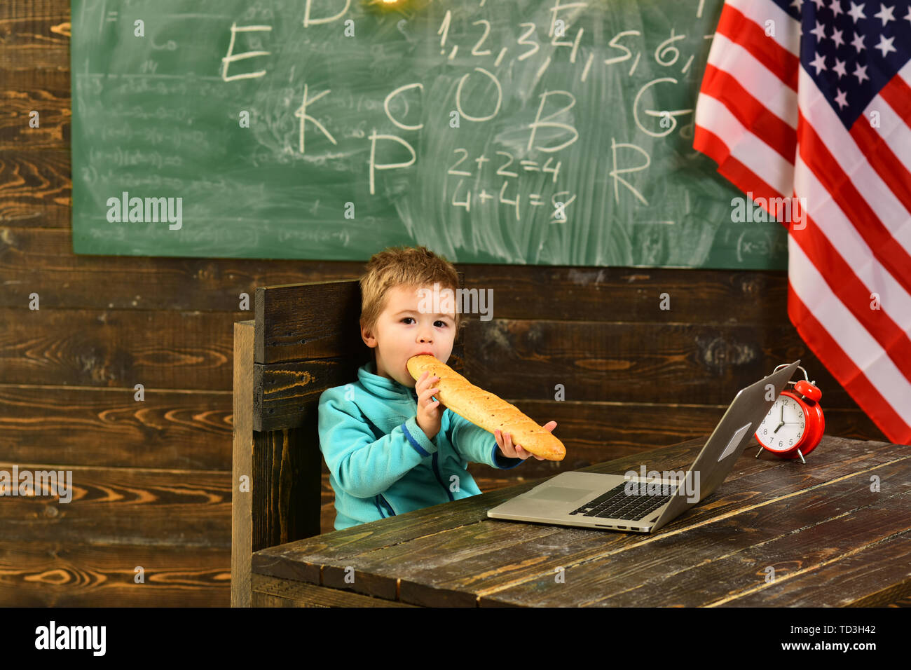 child with laptop and bread at american flag on independence day of usa. Stock Photo