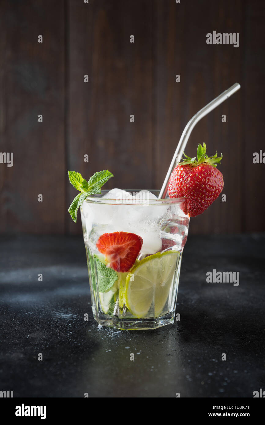 Detox lemonade or mojito with lime, lemon, strawberry in rocks glass. Summer healthy drink. Stock Photo