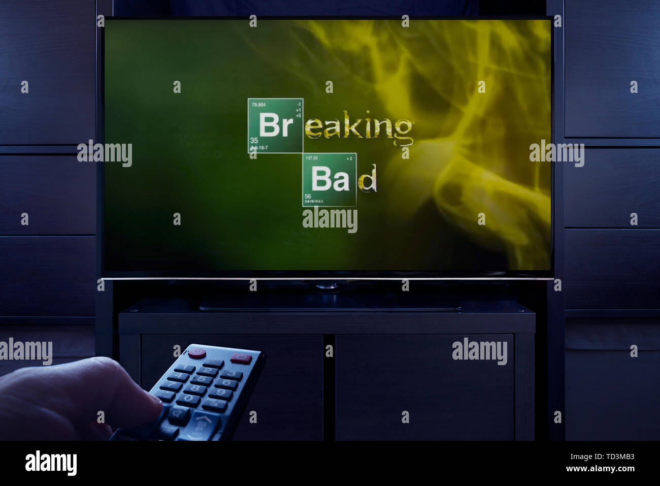 A man points a TV remote at the television which displays the Breaking Bad main title screen (Editorial use only). Stock Photo
