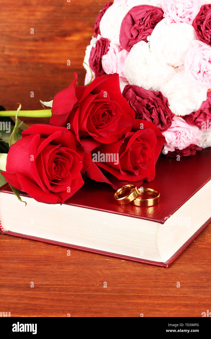 Wedding rings on bible with roses on wooden background Stock Photo