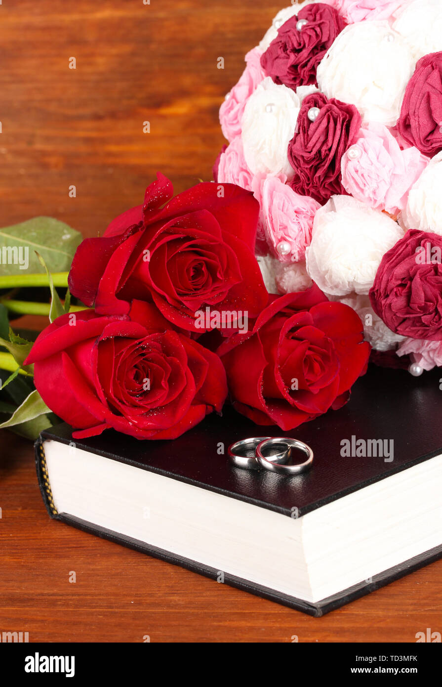 Wedding rings on bible with roses on wooden background Stock Photo