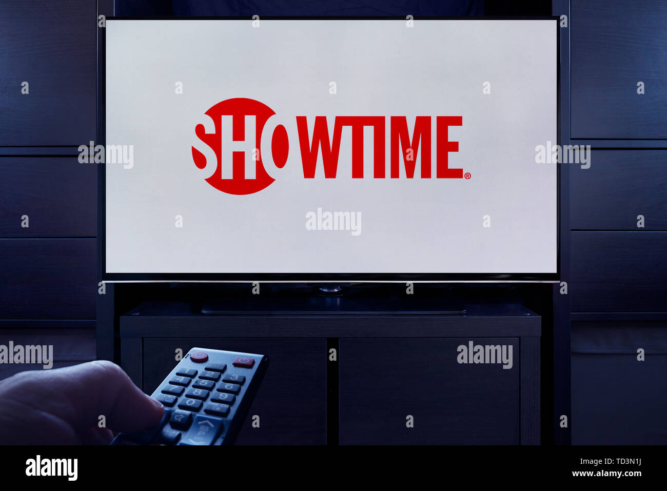 A man points a TV remote at the television which displays the logo for the Showtime on demand video streaming service (Editorial use only). Stock Photo