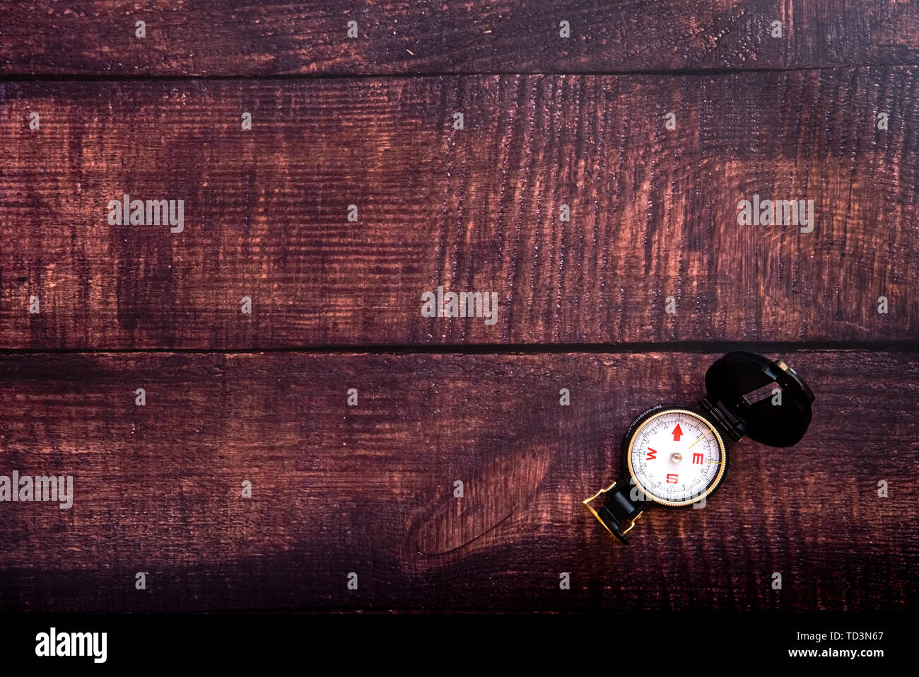 Isolated compass on a brown aged wooden table, copy space. Stock Photo