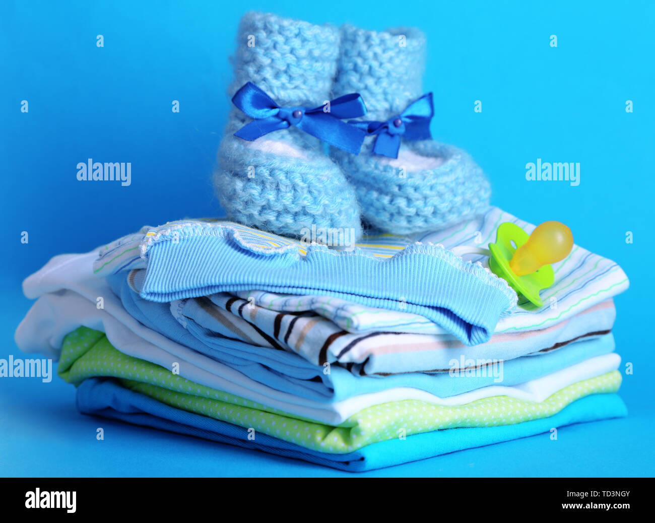 Pile of baby clothes on blue background Stock Photo Alamy