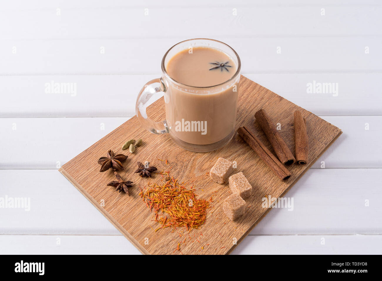 Indian traditional Masala chai tea in a glass mug and kitchen herbs