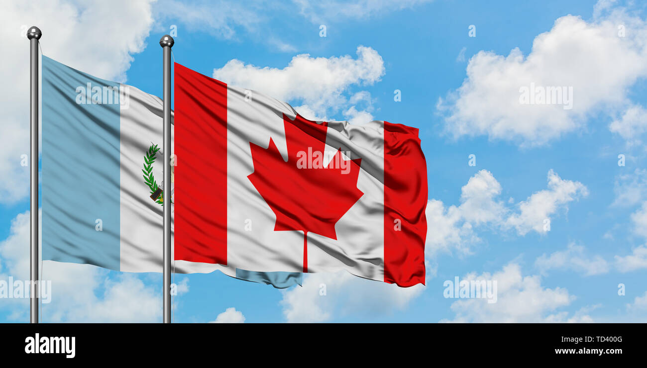 Guatemala and Canada flag waving in the wind against white cloudy blue sky together. Diplomacy concept, international relations. Stock Photo