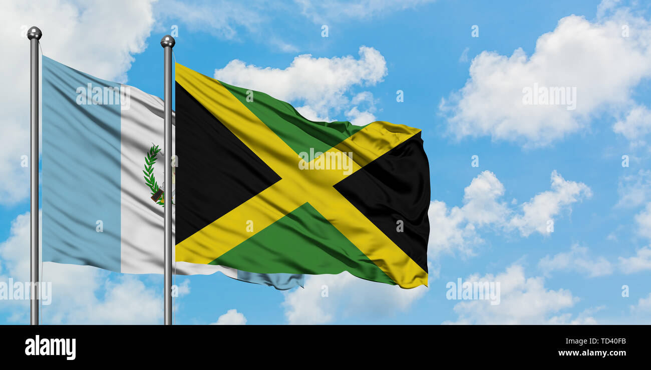 Guatemala and Jamaica flag waving in the wind against white cloudy blue sky together. Diplomacy concept, international relations. Stock Photo
