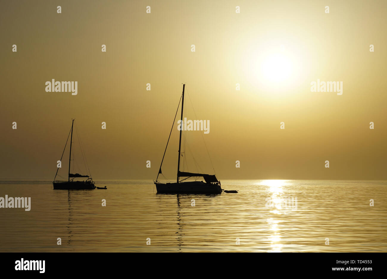 Beautiful summer sunset background in beige color tone with black contrast of silhouette of two yachts on the sea horizon line and free copy space Stock Photo