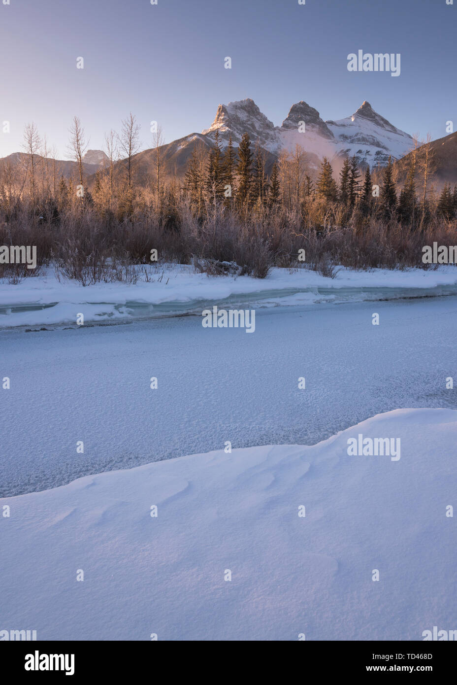 Winter sunrise with frozen Bow River and Three Sisters, Canmore, Alberta, Canadian Rockies, Canada, North America Stock Photo