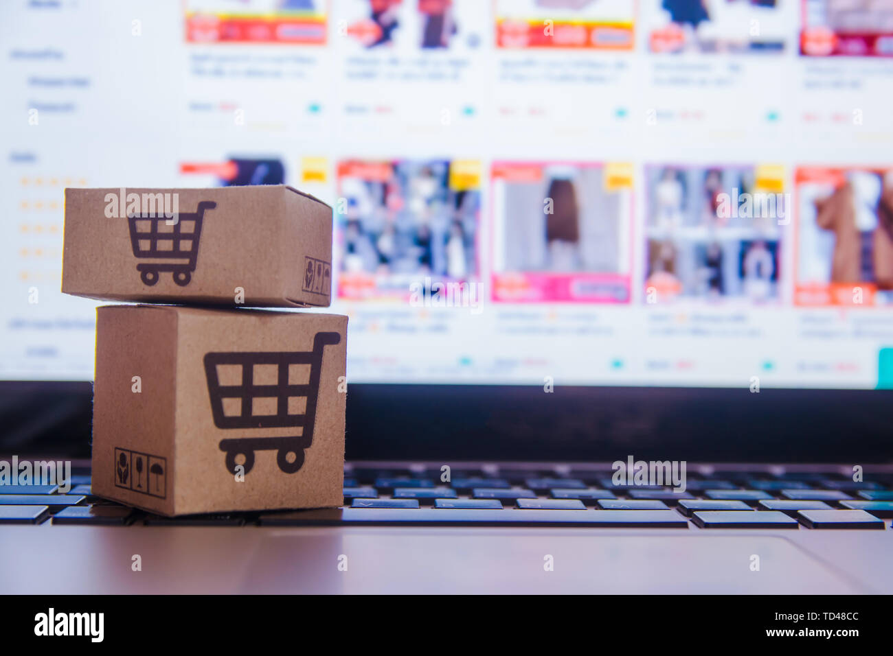 Online shopping - Paper cartons or parcel with a shopping cart logo on a laptop keyboard. Shopping service on The online web and offers home delivery. Stock Photo