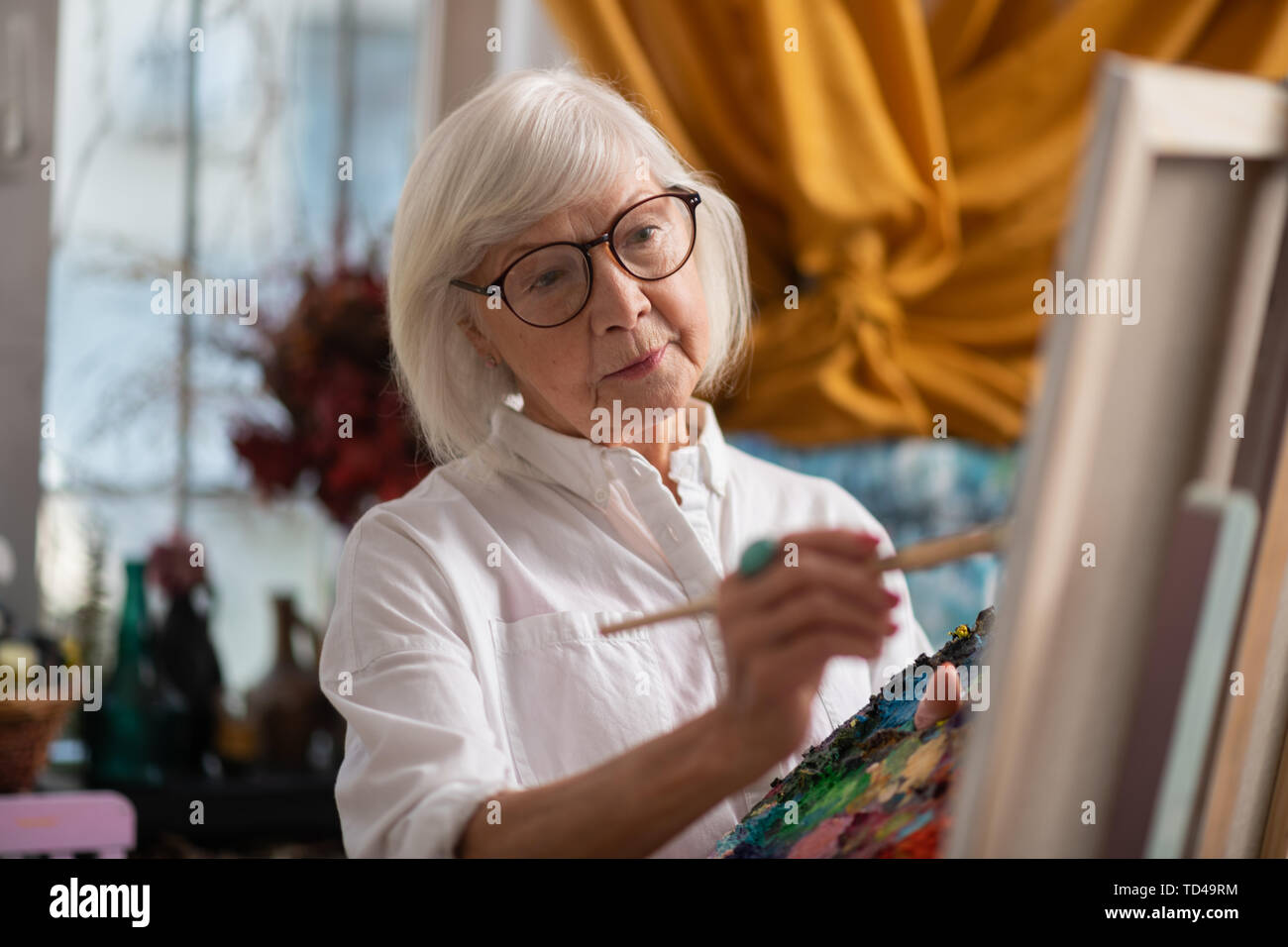 Painting in workshop. Dark-eyed aged woman painting in workshop feeling good and inspired Stock Photo