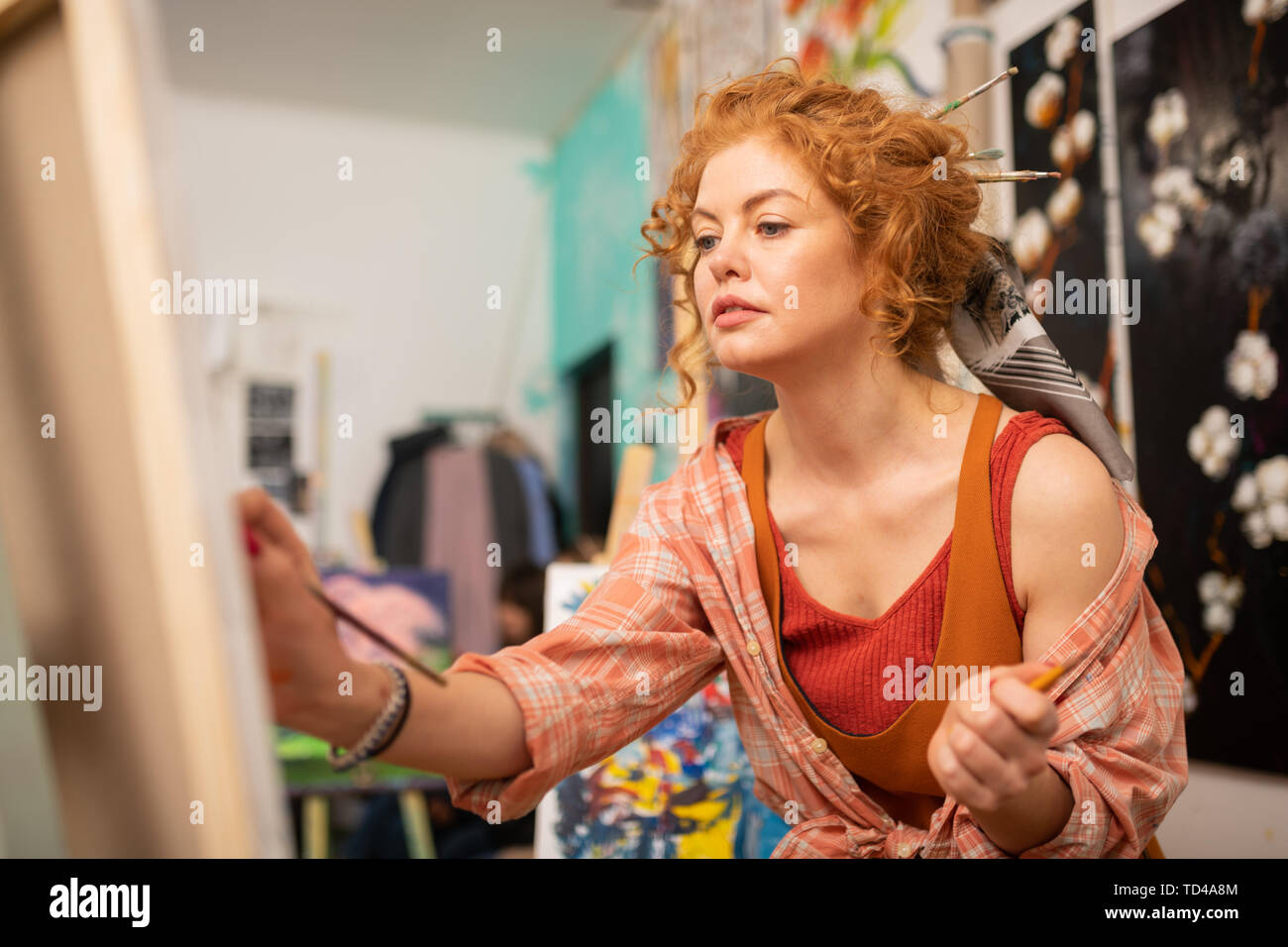 Dark-eyed artist. Dark-eyed artist with brassy hair feeling joyful while painting at the weekend Stock Photo