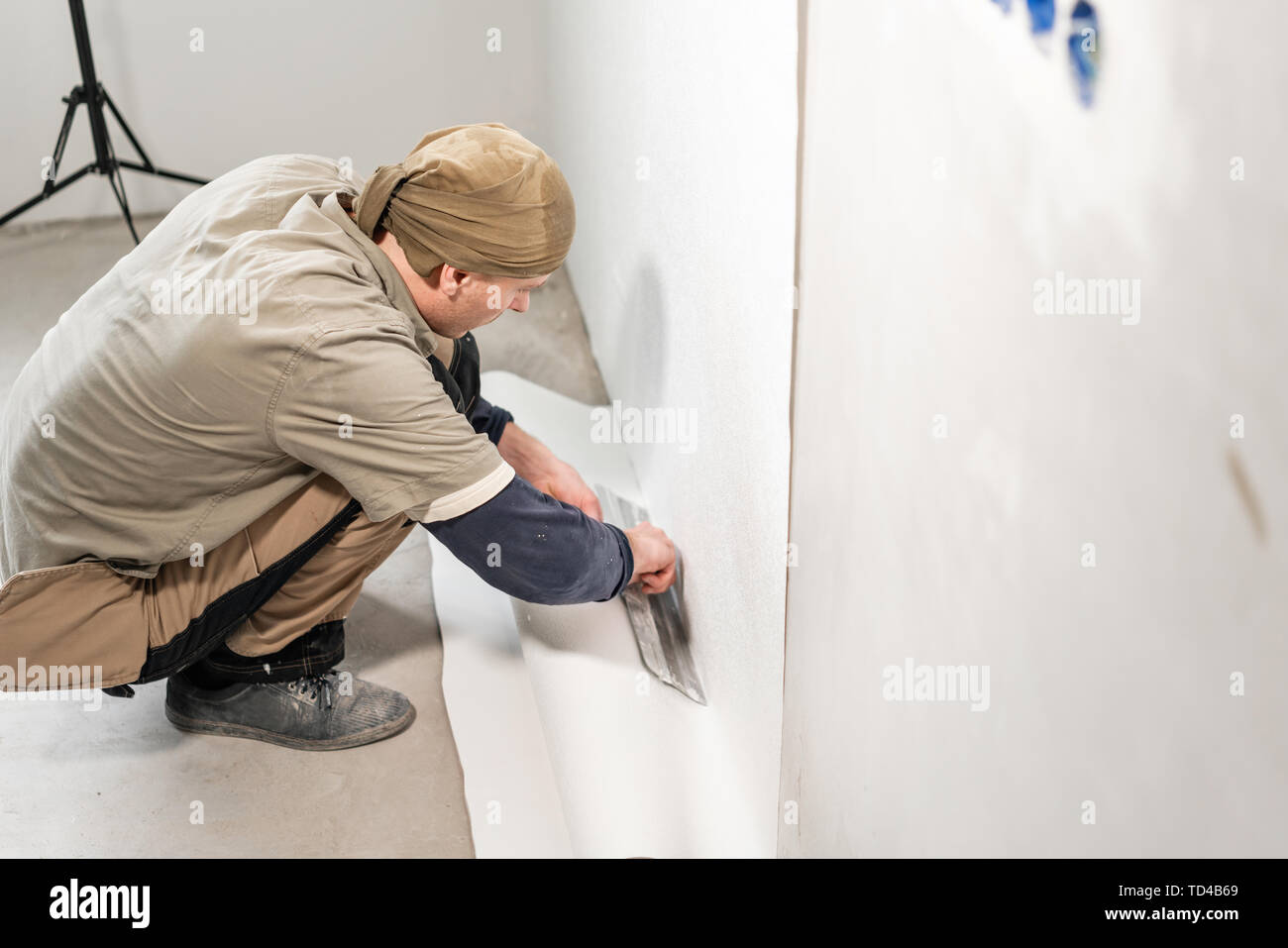 Worker applies a sheet of Wallpaper. Man glueing wallpapers on concrete
