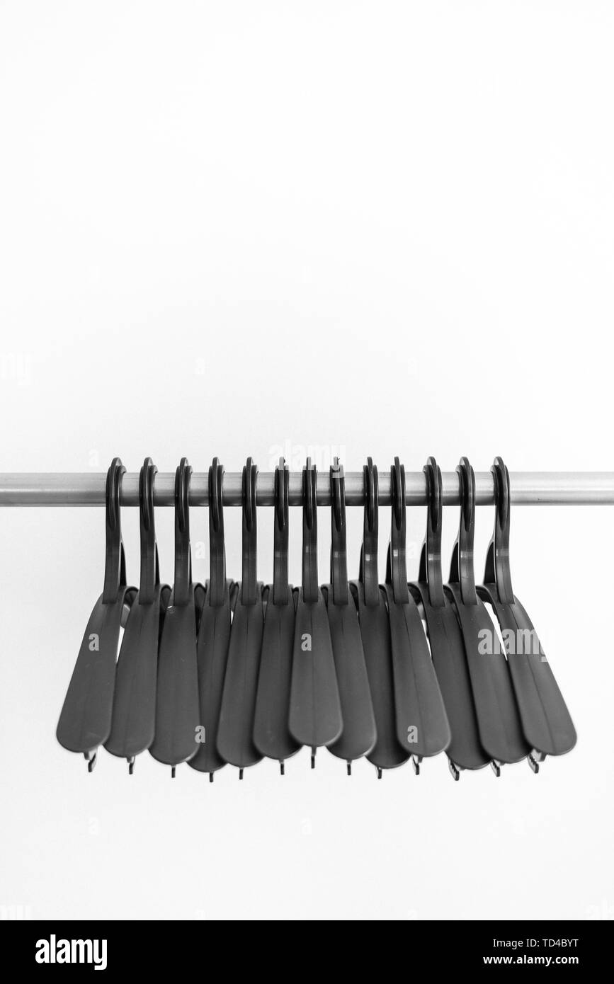 black plastic hangers hang on a light background. many different hangers. floor coat rack. black and white photo Stock Photo