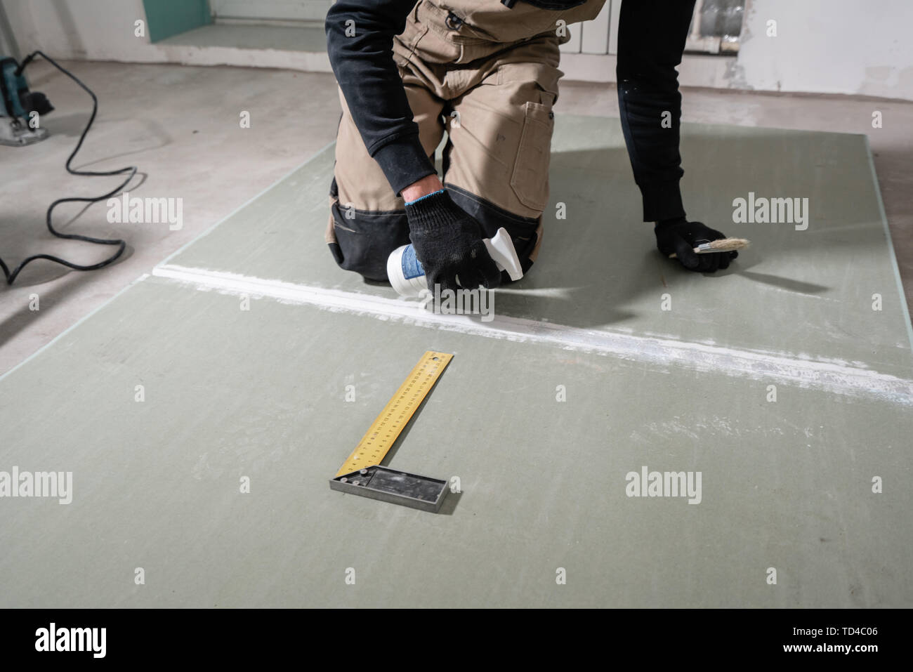 Worker is using a polyurethane foam for gluing drywall at degrees. Hand holding