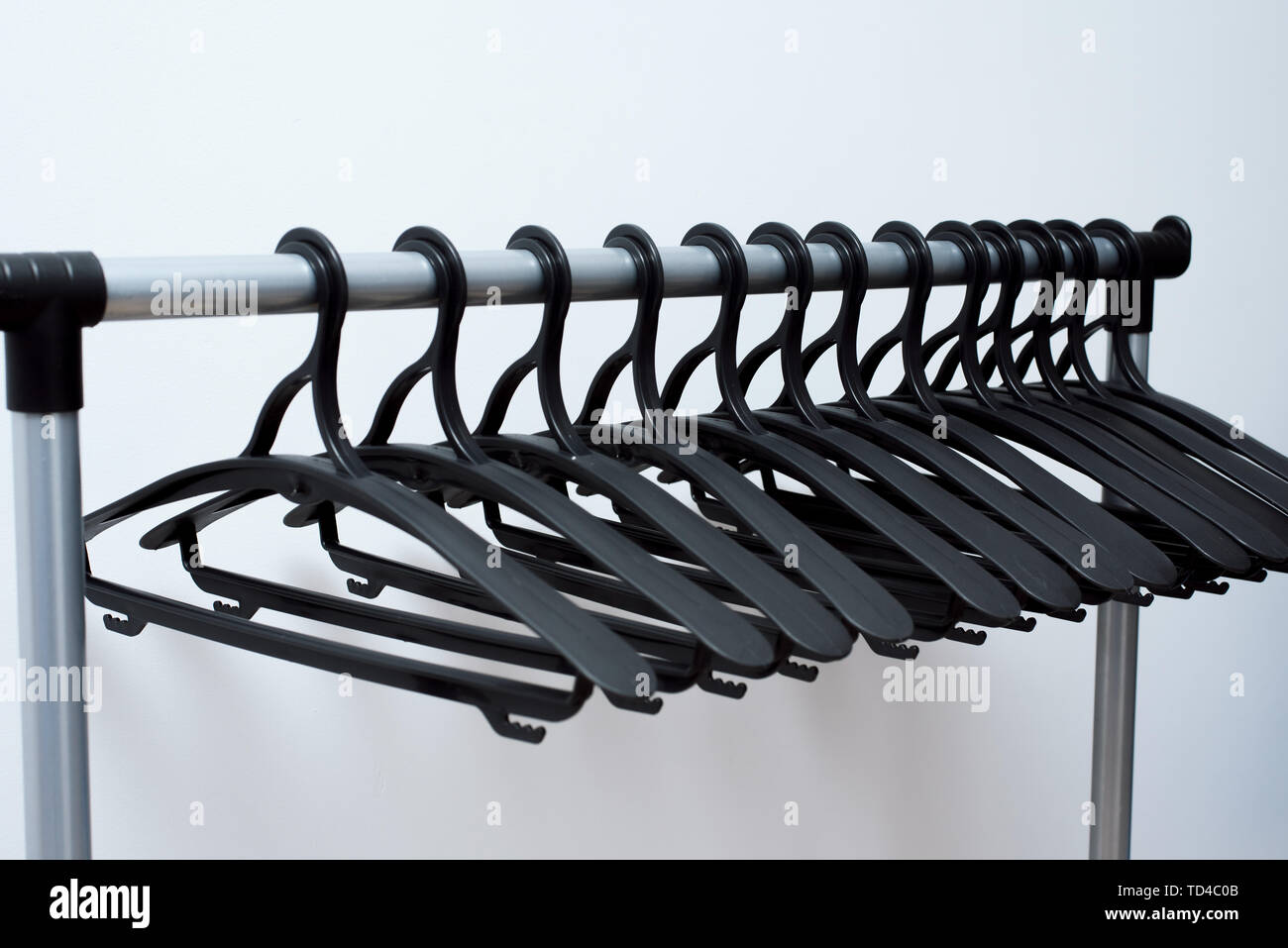 black plastic hangers hang on a light background. many different hangers. floor coat rack. Stock Photo