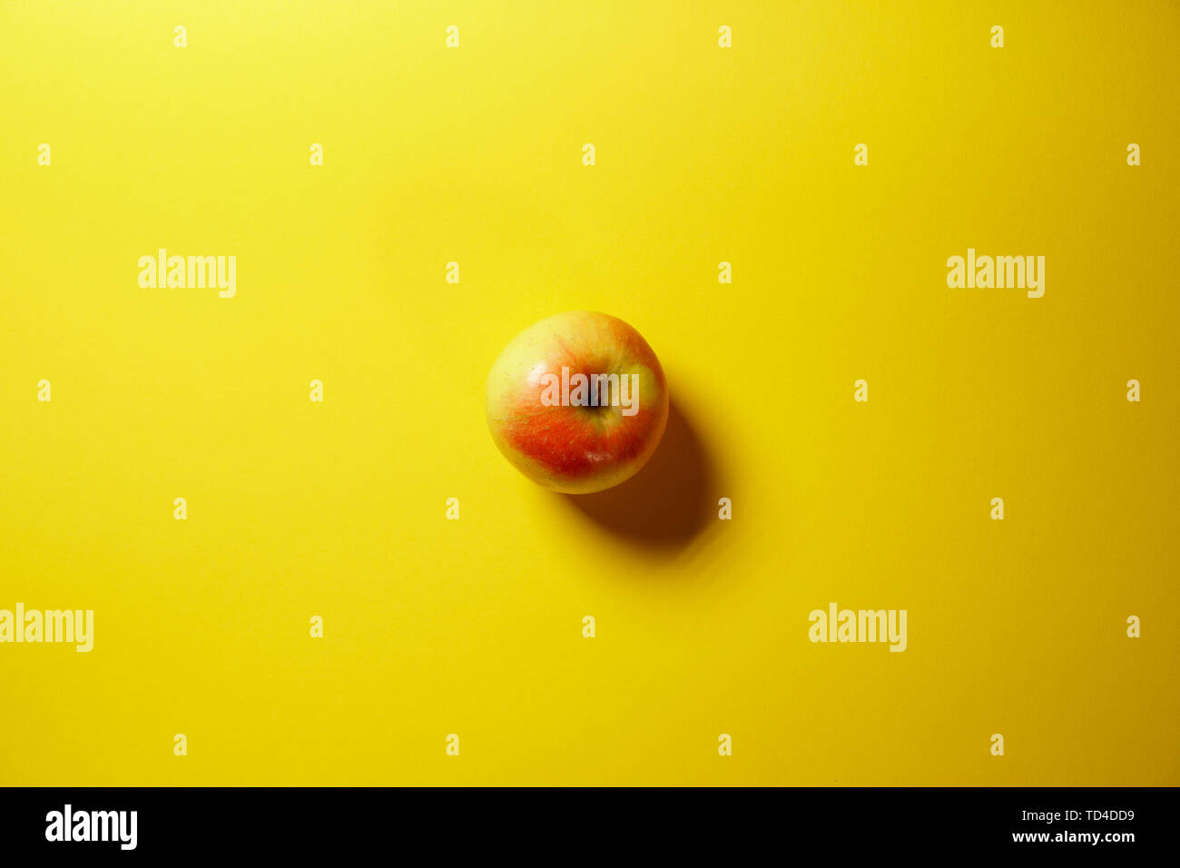 Single red apple isolated on yellow background Stock Photo