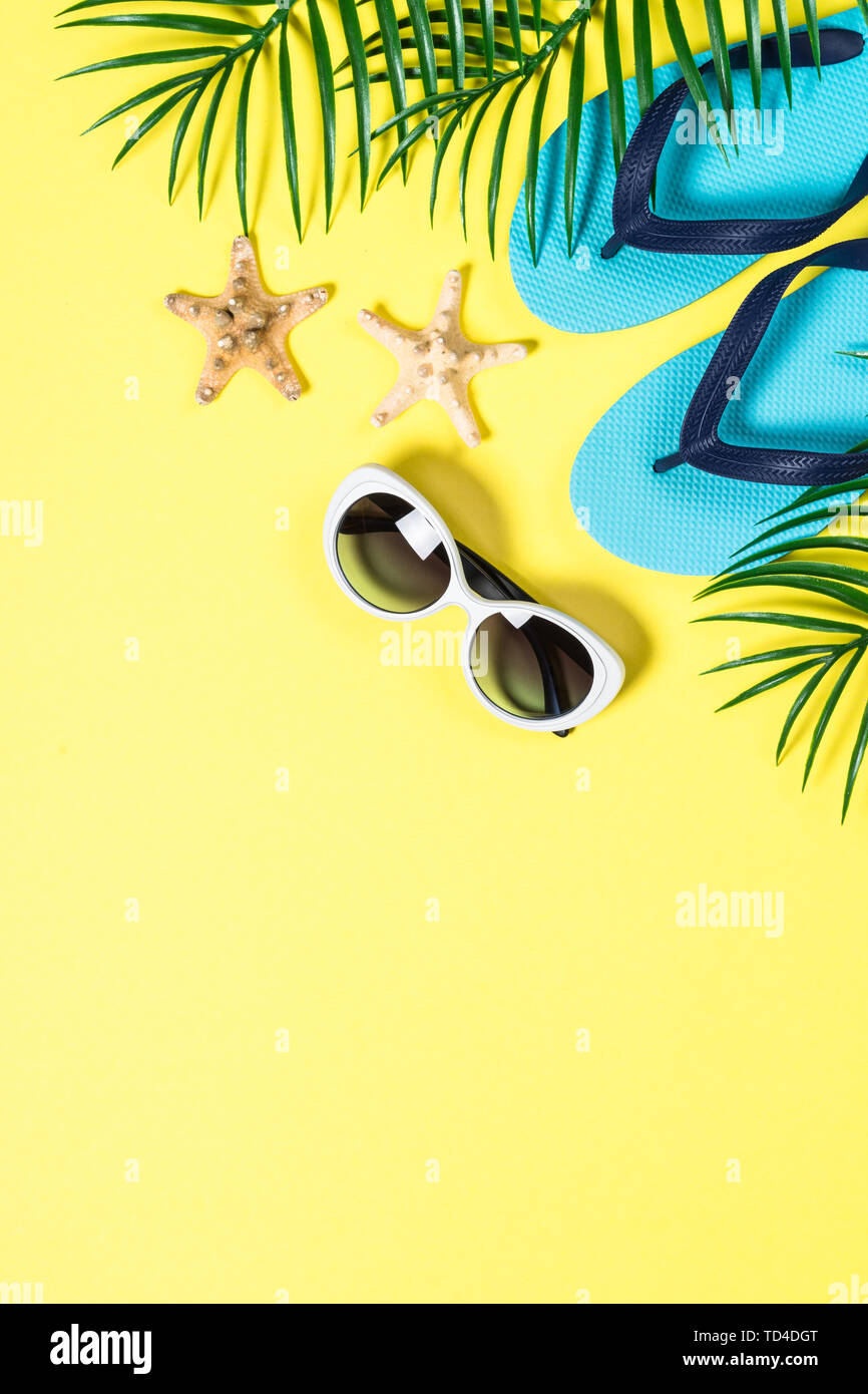 Tropical palm leaves, flip flops and sunglasses. Summer background. Flat lay image with copy space. Stock Photo