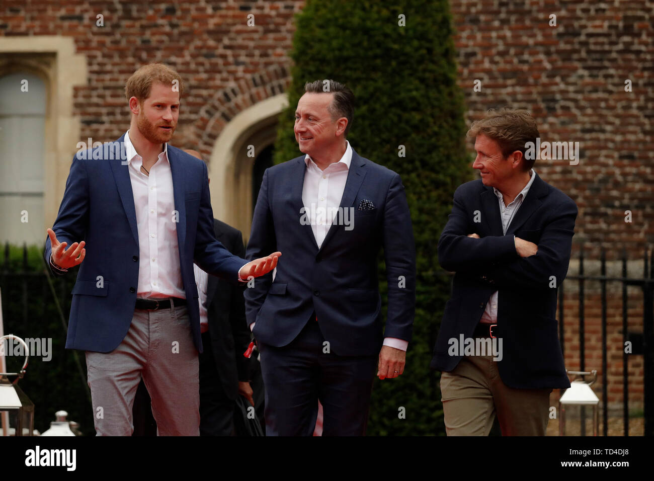 The Duke of Sussex walks with the Managing Director of Audi UK Andrew Doyle (centre) and the Chairman of Sentebale Johnny Hornby before a concert hosted by Sentebale in Hampton Court Palace in East Molesey, to raise awareness and vital funds for the Duke's charity, Sentebale, which helps young people in southern Africa affected by HIV. Stock Photo