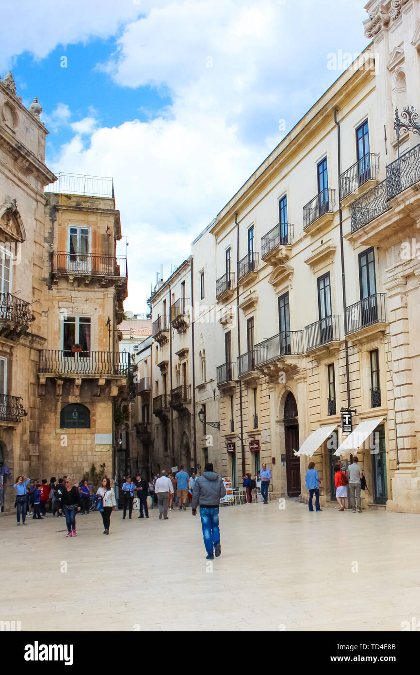 Syracuse, Sicily, Italy - Apr 10th 2019: Tourists walking on the Piazza Duomo Square in the old town. The historical center of the beautiful city is located on famous Ortigia Island. Popular spot. Stock Photo