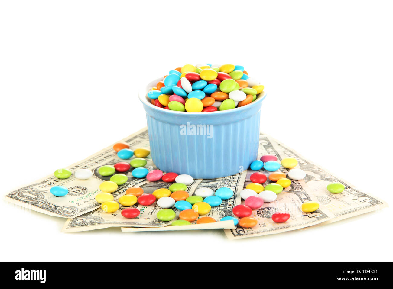 Bowl with colorful candies standing on dollar banknotes isolated on ...