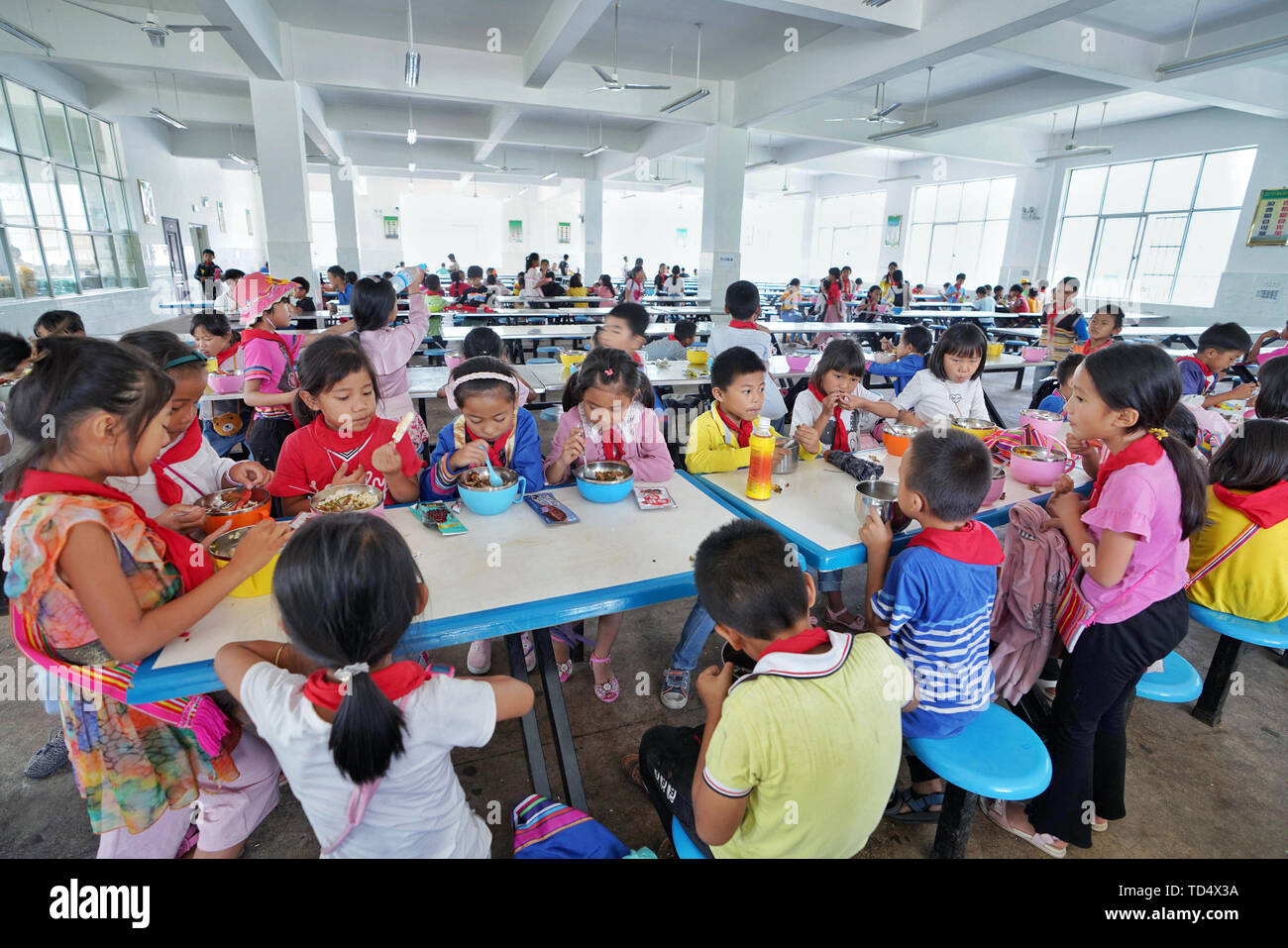 (190612) -- JINGHONG, June 12, 2019 (Xinhua) -- Pupils have lunch at a school in Jino Ethnic Township on Jino Mountain in Jinghong of Xishuangbanna Dai Autonomous Prefecture, southwest China's Yunnan Province, June 11, 2019. With a population of slightly over 20,000, the Jino people had only been officially acknowledged in 1979 as an independent ethnic group of China. Until 1949, most of them had lived for generations in primitive mountain tribes in southwest China's Yunnan Province. Currently, the primary education in Jino Ethnic Township achieved 100 percent coverage for all school-age child Stock Photo