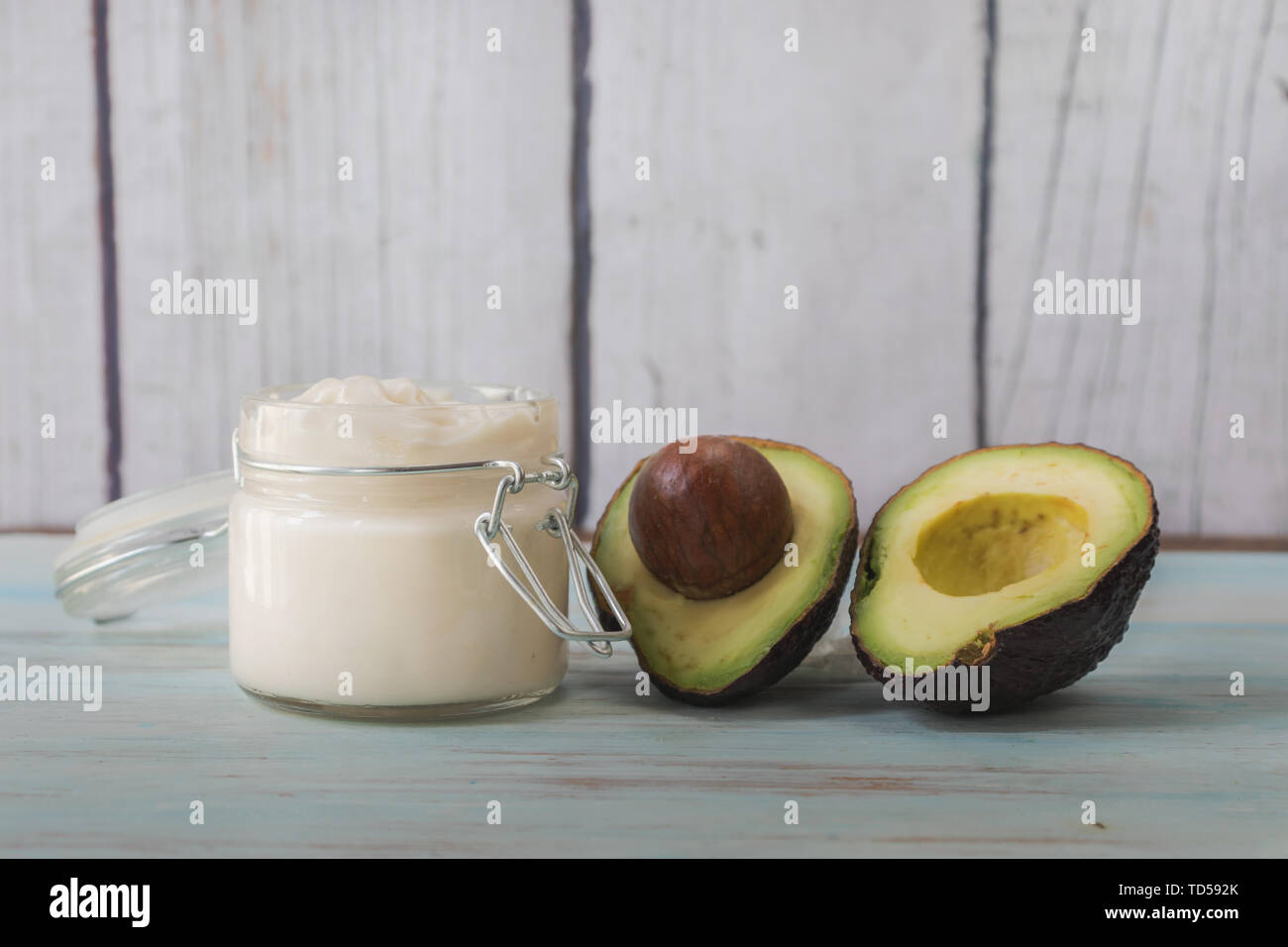 Homemade facial cream of avocado oil. Homemade cream in glass jar an avocado split in half Stock