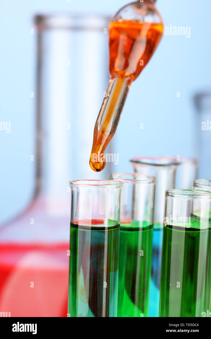 Laboratory pipette with drop of color liquid over glass test tubes ...