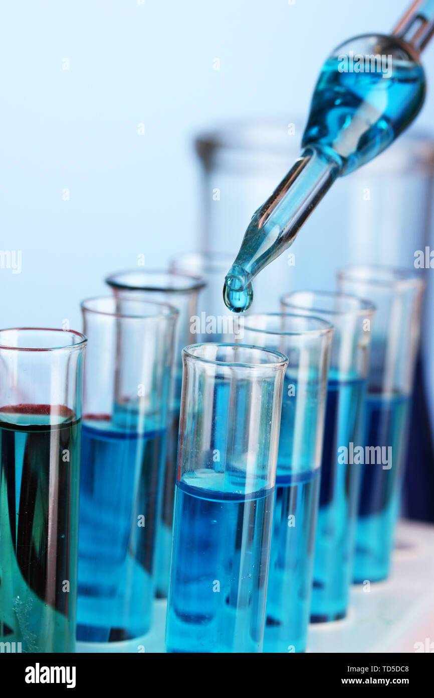 Laboratory pipette with drop of color liquid over glass test tubes ...