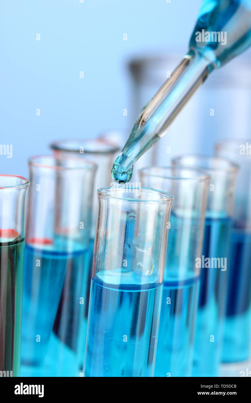 Laboratory pipette with drop of color liquid over glass test tubes ...