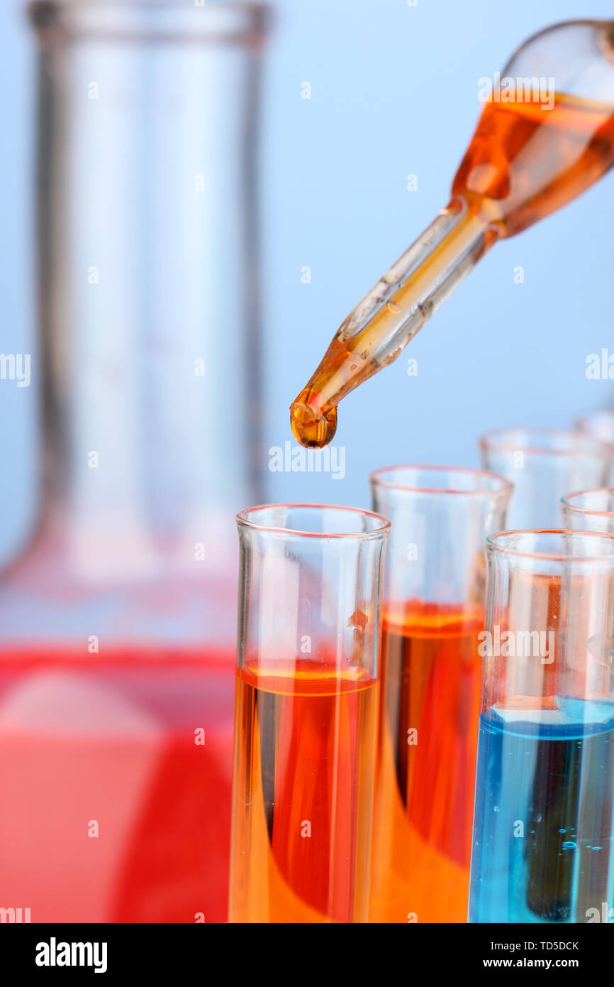 Laboratory pipette with drop of color liquid over glass test tubes ...