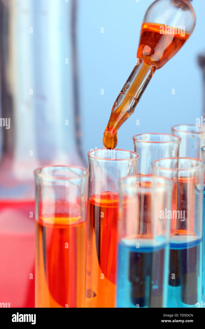Laboratory pipette with drop of color liquid over glass test tubes ...