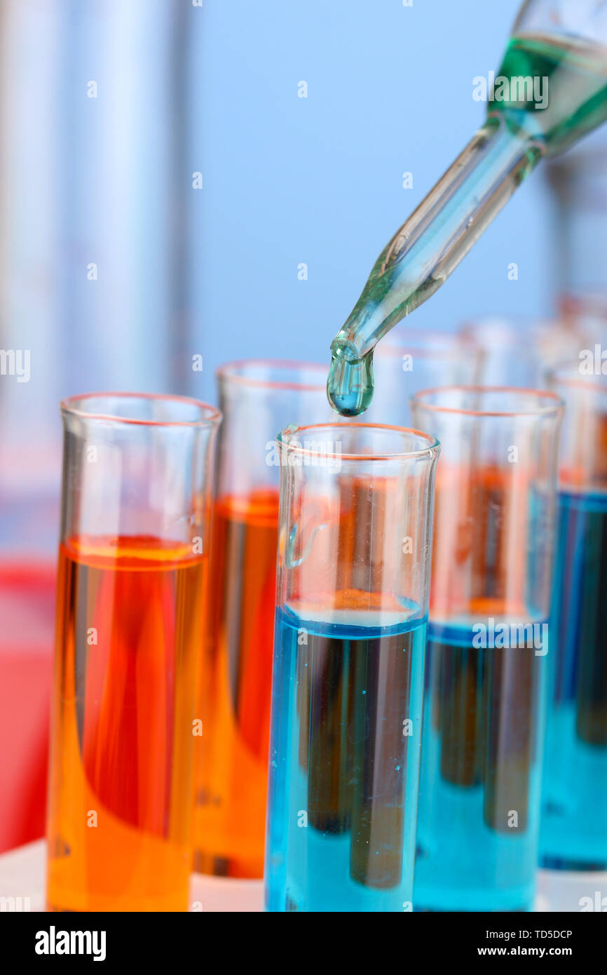Laboratory pipette with drop of color liquid over glass test tubes ...