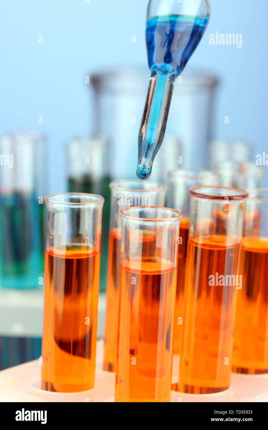 Laboratory pipette with drop of color liquid over glass test tubes ...