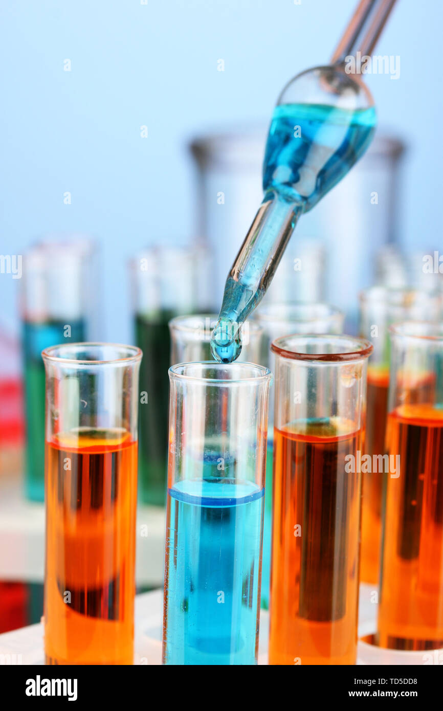 Laboratory pipette with drop of color liquid over glass test tubes ...