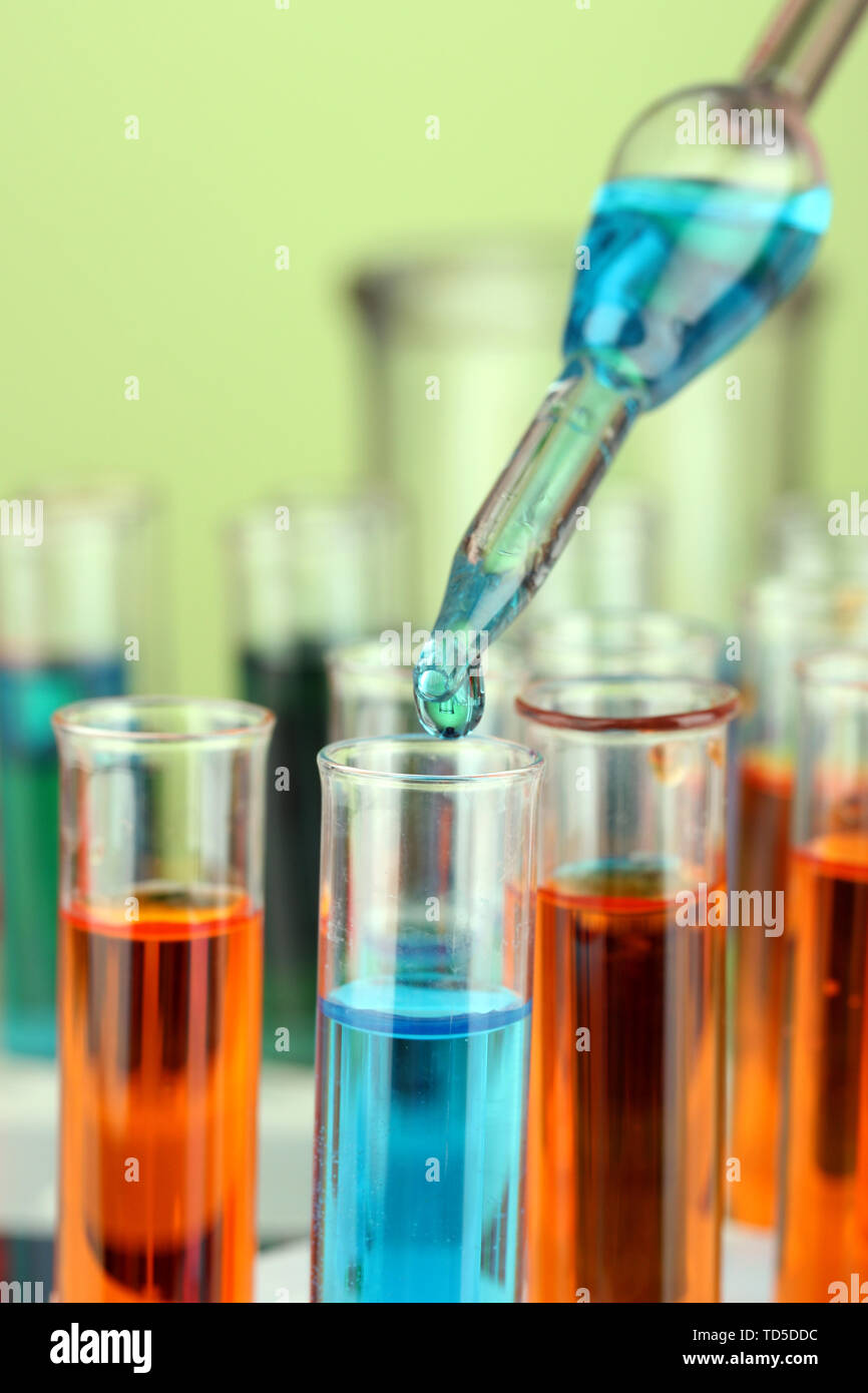 Laboratory pipette with drop of color liquid over glass test tubes ...