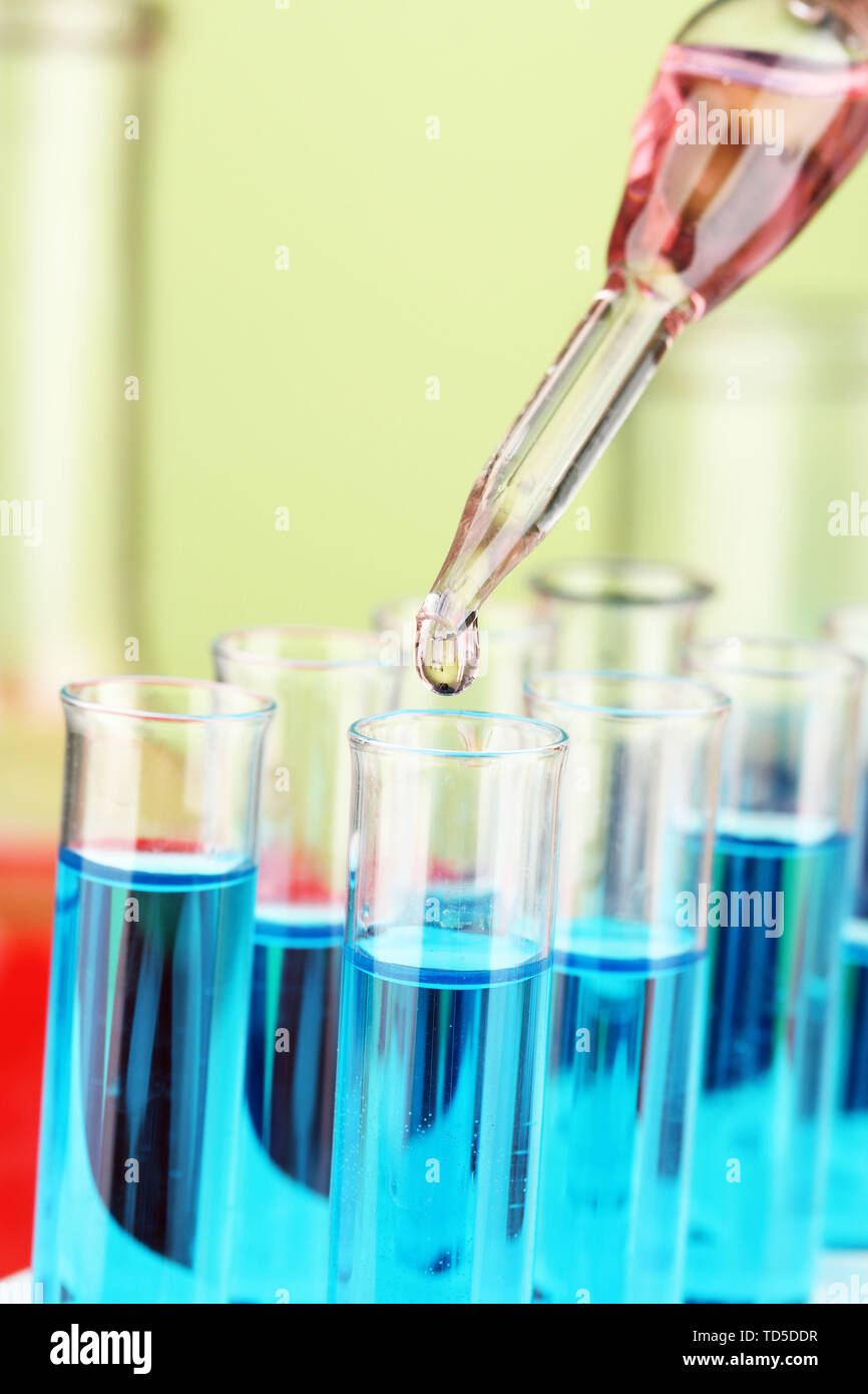 Laboratory pipette with drop of color liquid over glass test tubes ...