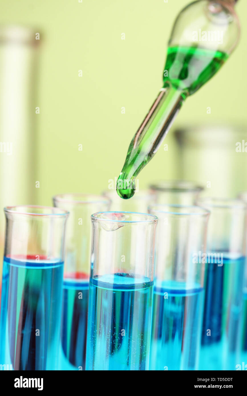 Laboratory pipette with drop of color liquid over glass test tubes ...