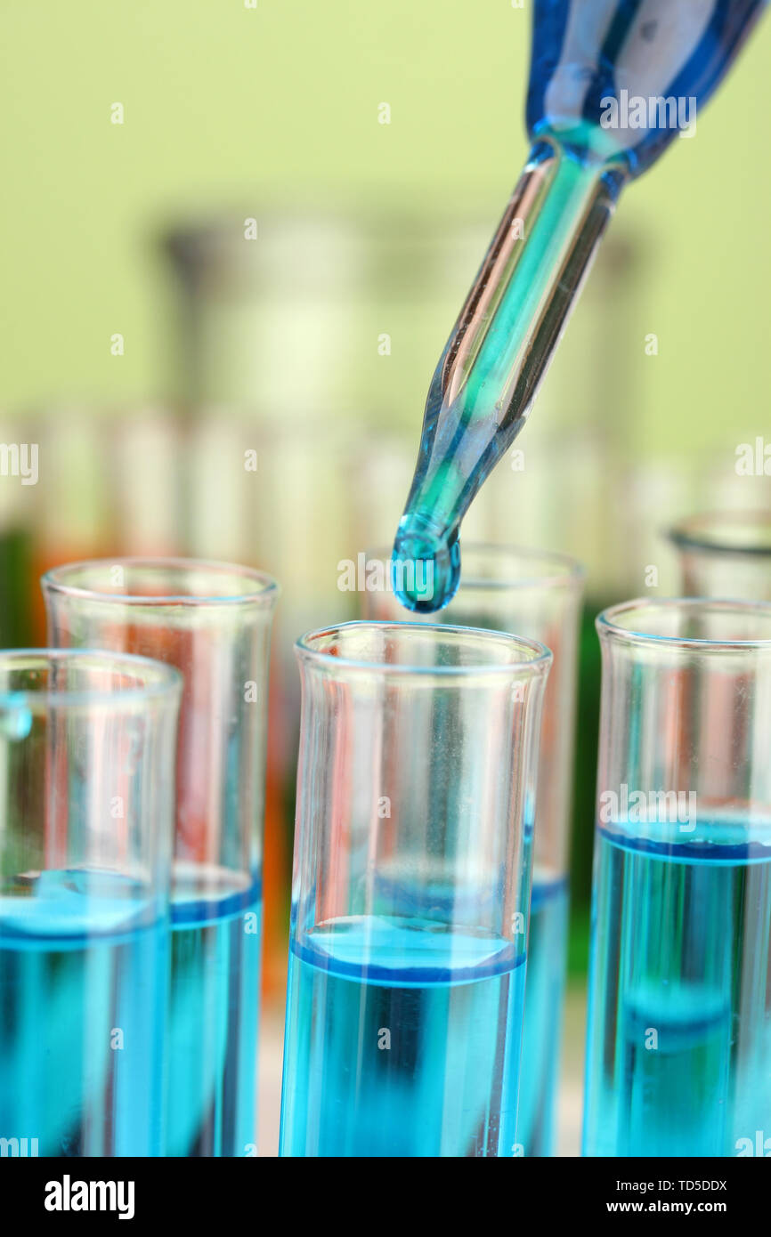 Laboratory pipette with drop of color liquid over glass test tubes ...