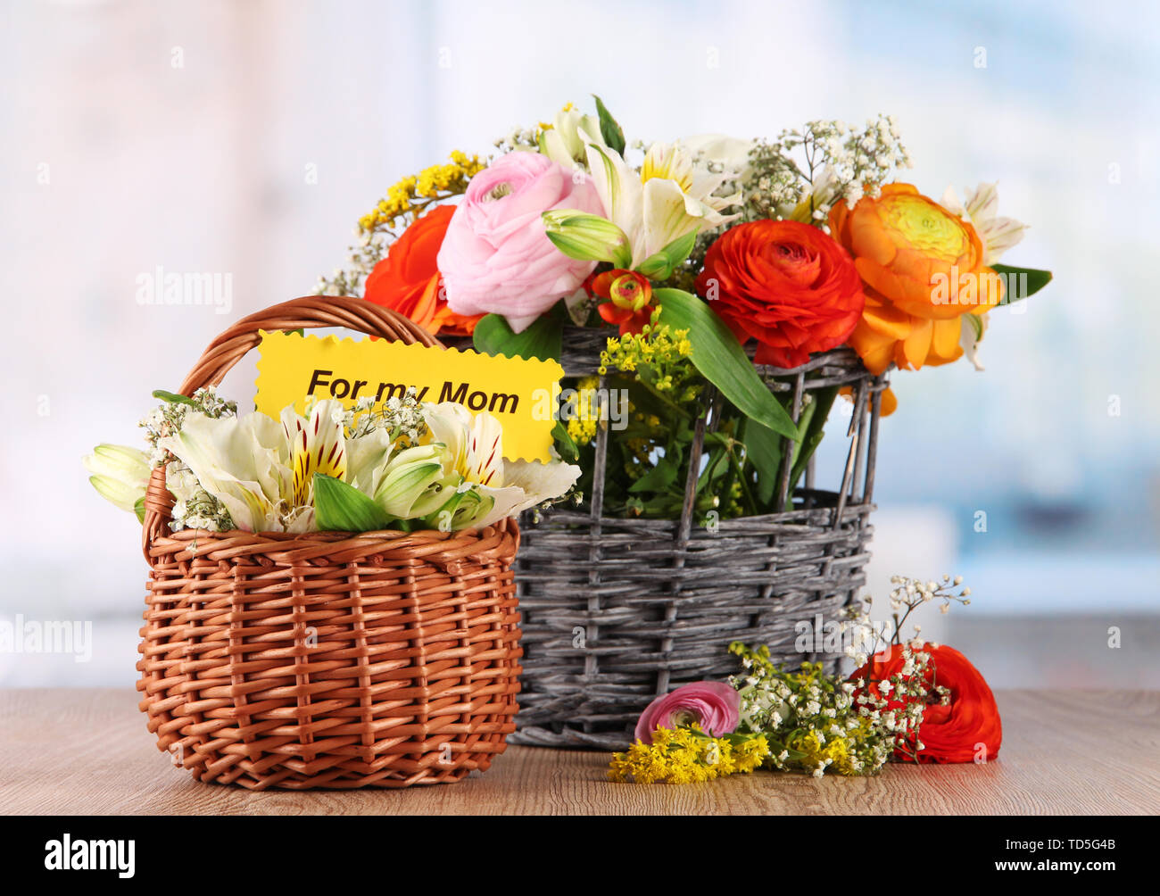 Many different flowers in baskets on room background Stock Photo