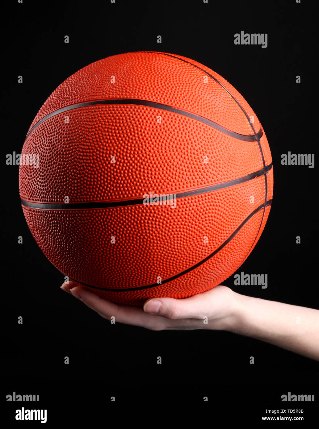 Basketball in woman hand on black background Stock Photo - Alamy